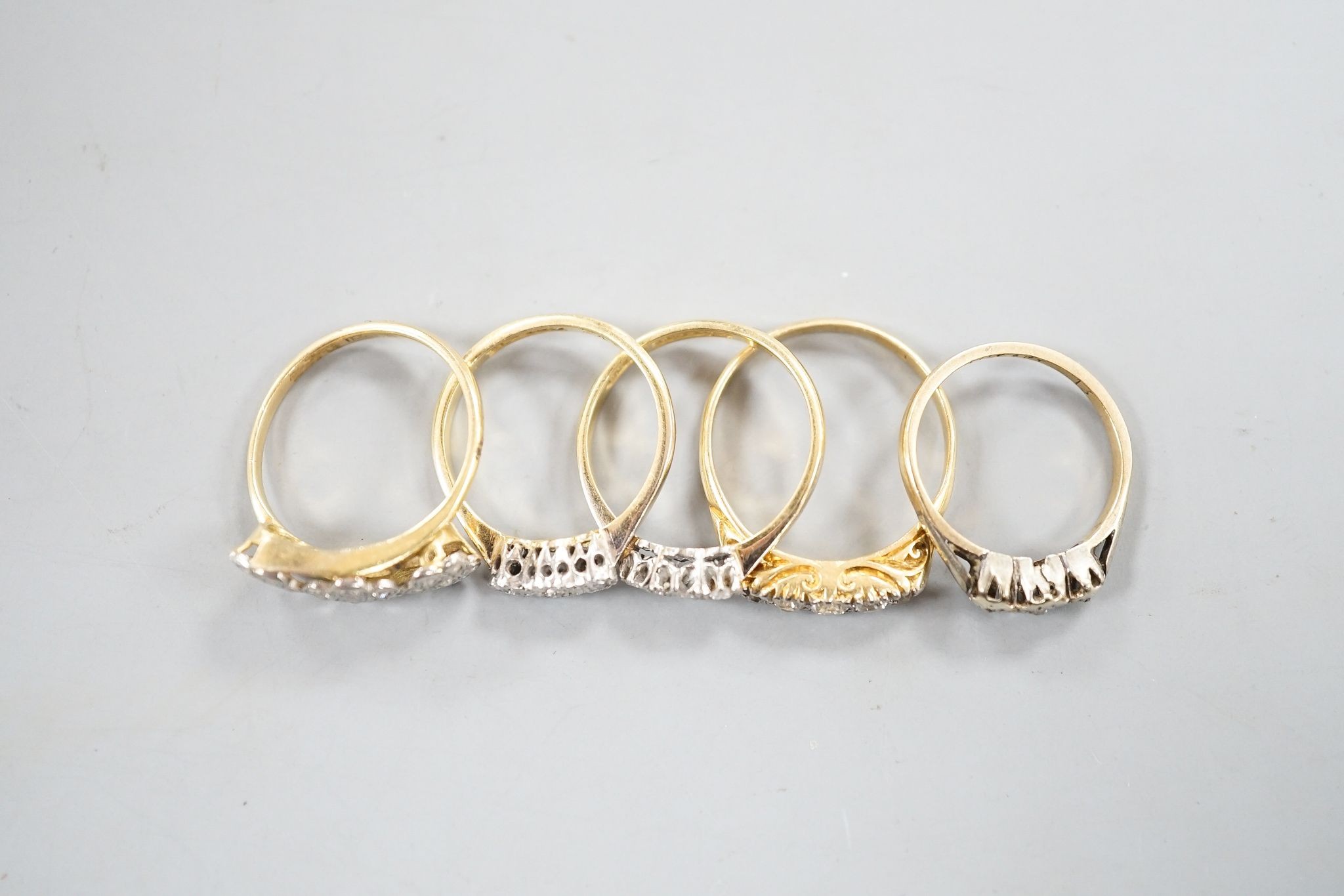 An early 20th century yellow metal and graduated five stone diamond set half hoop ring, size Q, gross 3.8 grams, three other 18ct and diamond chip set rings, gross 8 grams and a 9ct and diamond chip ring, gross 1.2 grams